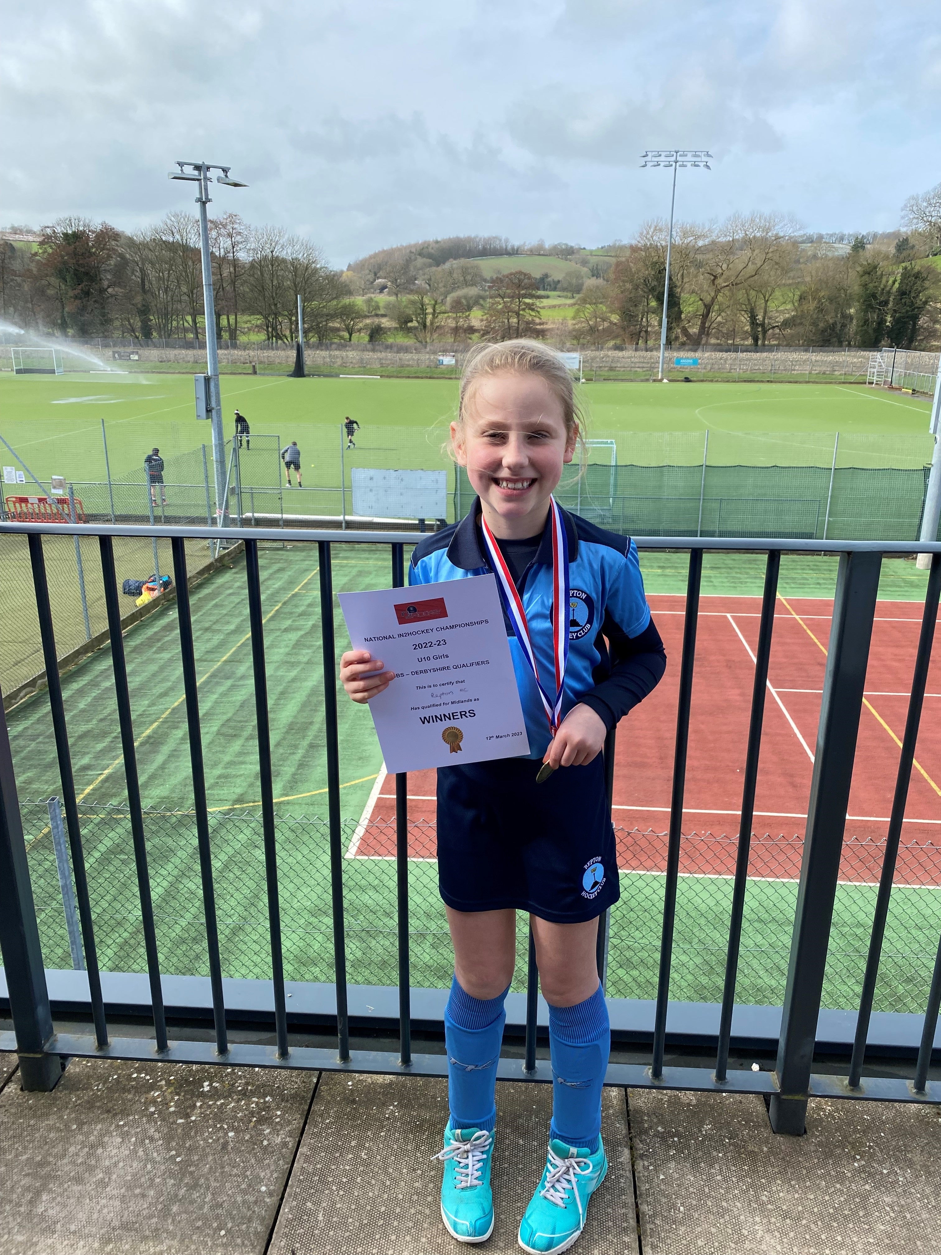Ella with an award by a hockey pitch
